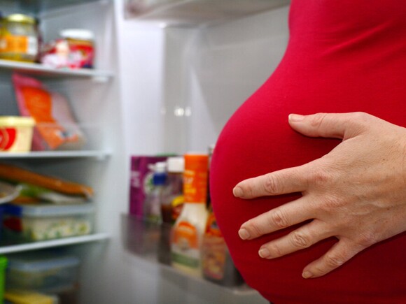 Pregnant woman looking into opened fridge