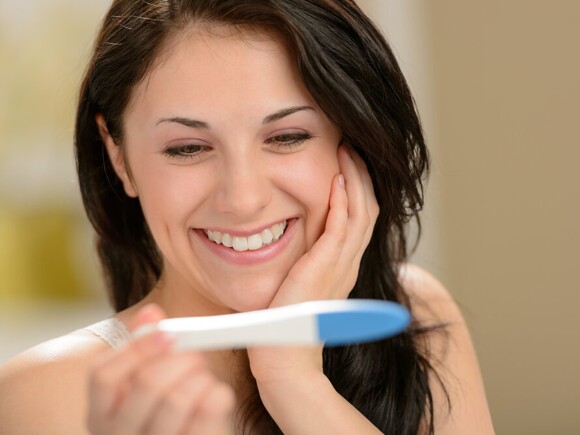 Happy woman holding pregnancy test
