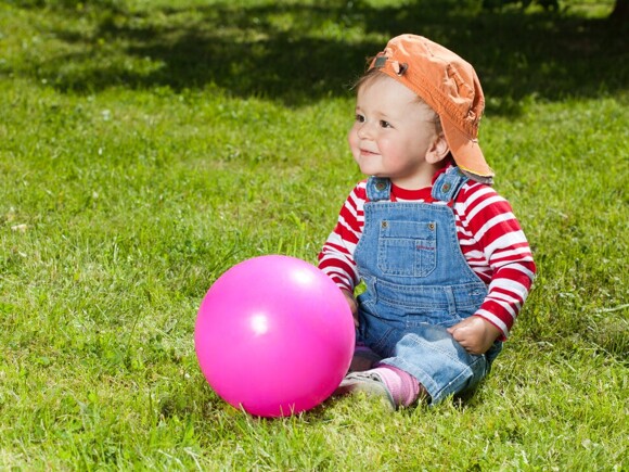 Baby sitting on grass with ball