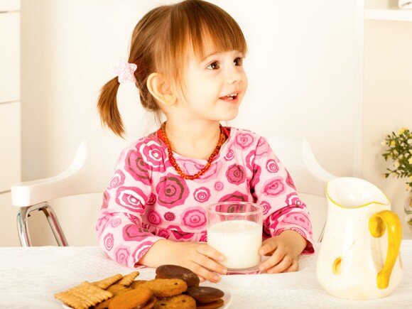 Little girl having snack with milk and cookies