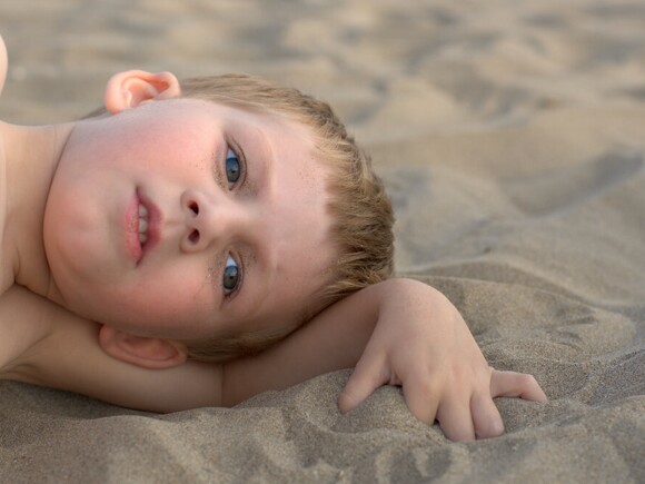 Baby boy lying on sand