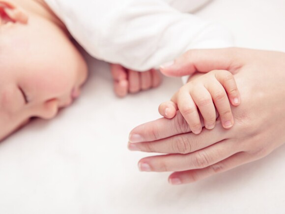 Mother holding sleeping baby hand
