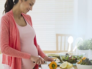 Pregnant woman cutting vegetable