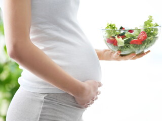 Pregnant woman with bowl of vegetable salad