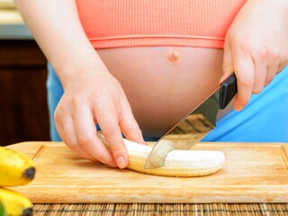 Pregnant woman cutting banana