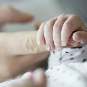 Baby holding mothers finger