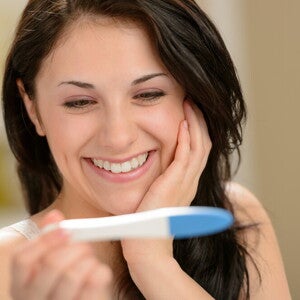 Happy woman holding pregnancy test