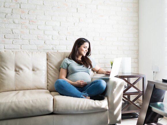 pregnant lady sitting on sofa with laptop