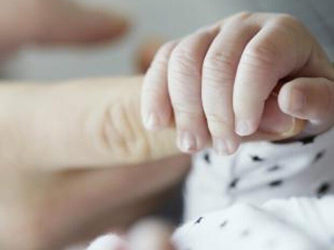 Baby holding mothers finger